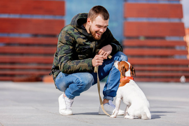 hombre con su perro, Jack Russell Terrier, en la calle de la ciudad
 - Foto, Imagen