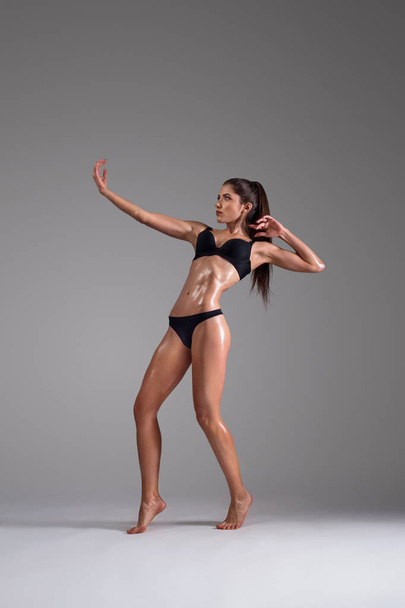 Fitness dancer and fashion model woman in bikini. Female with wet skin in lingerie posing in studio. - Фото, изображение