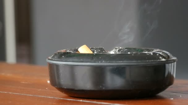 Rookt een sigaret Butt in een zwarte asbak op een straat close-up te bekijken. - Video