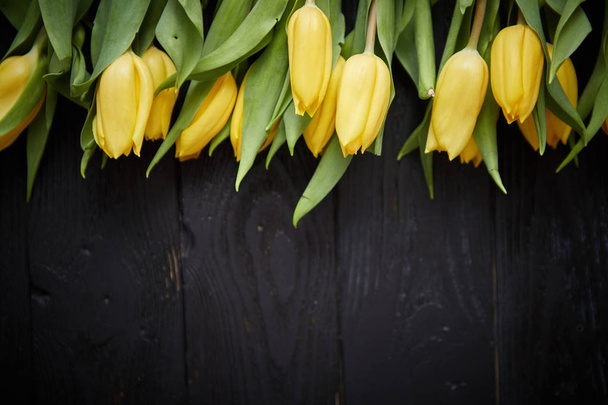 Красивые желтые тюльпаны на черном деревенском деревянном фоне. Вид сверху
 - Фото, изображение
