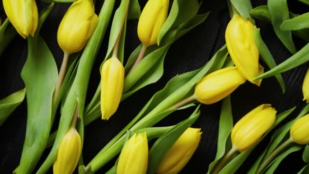 Beautiful yellow tulips on black rustic wooden background. Top view - Footage, Video