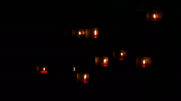 Bruciare belle candele rosse rotonde di preghiera in una nicchia speciale nel buio di una chiesa cattolica
. - Filmati, video