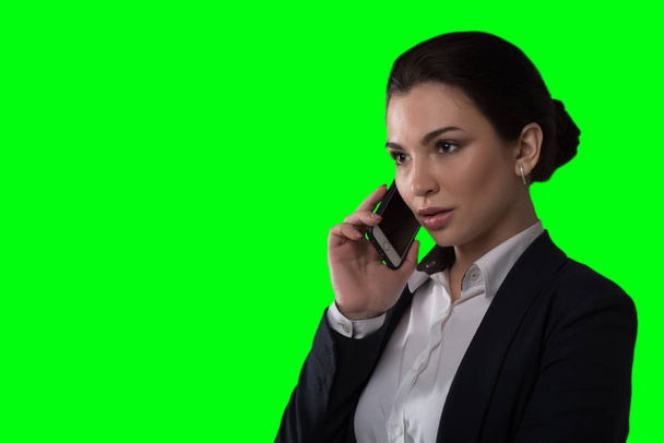 Dama młody biznes mówi przez telefon i działa na zielonym tle - Zdjęcie, obraz