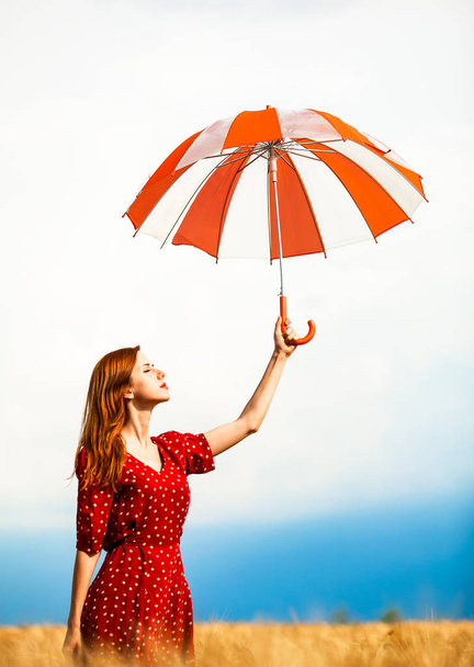 κοκκινομάλλα κοπέλα με ομπρέλα στο πεδίο - Φωτογραφία, εικόνα