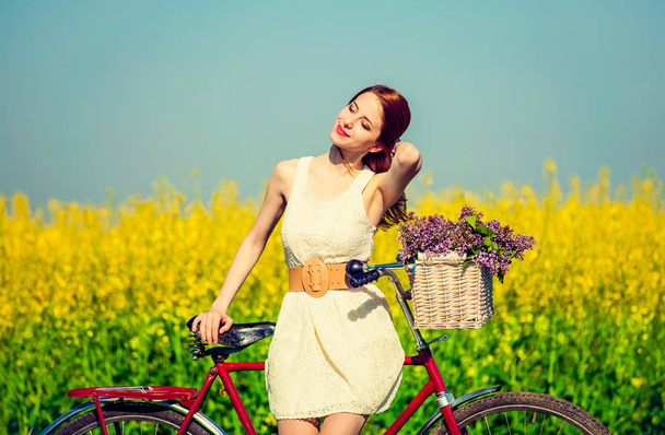 Redhead girl with bike and flowers in basket  - Photo, Image
