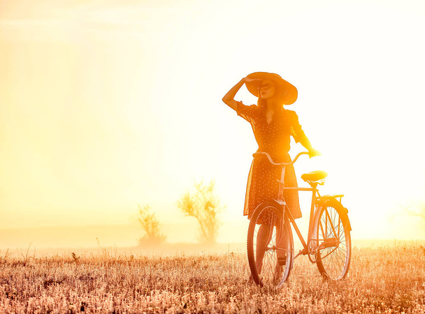 Girl on a bike in the countryside in sunrise time - Photo, Image