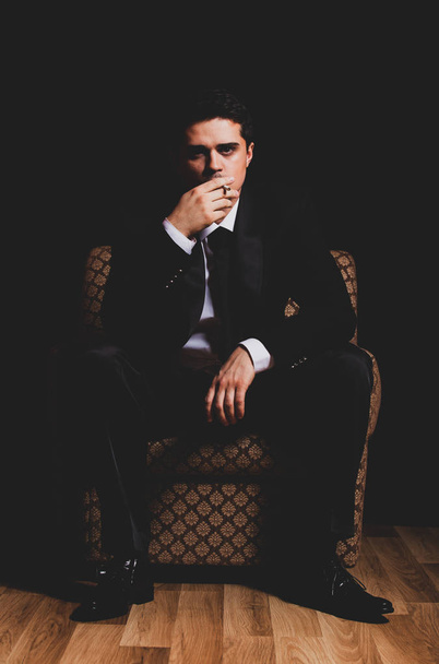 mężczyzna z papierosem, siedząc w fotelu vintage - Zdjęcie, obraz
