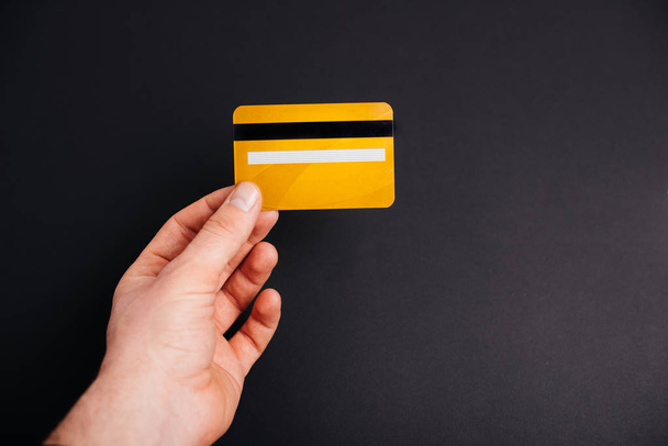 Ember kezében egy sárga hitelkártya fekete elszigetelt háttér  - Fotó, kép
