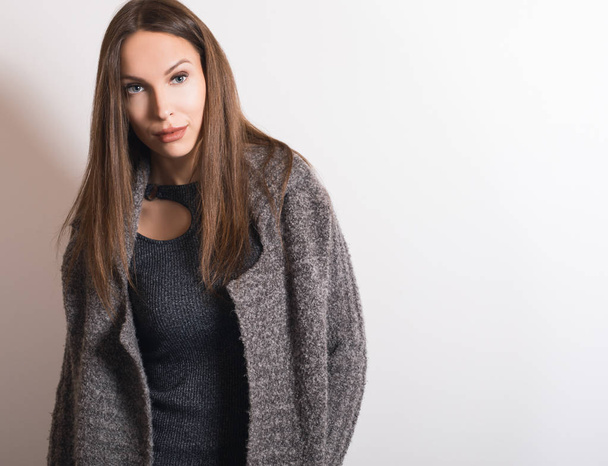 Beautiful young girl in gray coat posing in studio. - Foto, imagen
