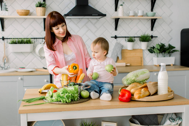 Note di alimentazione. Felice madre di famiglia e bambina prepara insalata di verdure in cucina
 - Foto, immagini