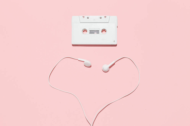 White audio cassette and heart shape of headphones on a pink background - Photo, Image