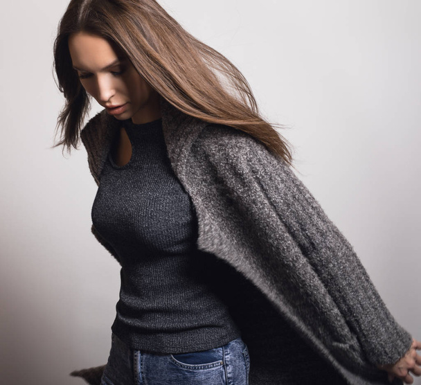 Beautiful young girl in gray coat posing in studio. - Фото, зображення