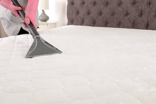 Woman disinfecting mattress with vacuum cleaner, closeup. Space for text - Foto, Imagem
