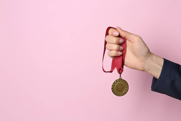 Woman holding golden medal on color background, closeup. Space for text - Fotografie, Obrázek