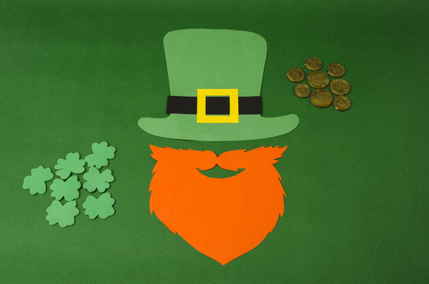 聖パトリックの日の概念。紙聖パトリックの日-性愛者の小道具: 緑の小児の帽子、ひげのあるオレンジ色のひげ、コインとクローバー、アイルランドの伝統的な休日の象徴として木製の背景 - 写真・画像