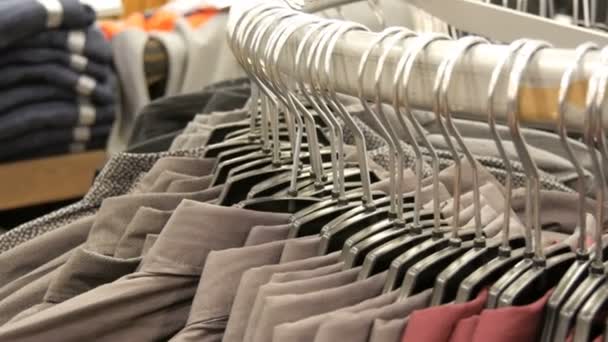 Fila di varie camicie alla moda da uomo su un enorme appendiabiti nel negozio di abbigliamento da uomo nel centro commerciale
. - Filmati, video