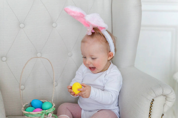 Menina criança vestindo orelhas de coelho no dia de Páscoa e brincando com ovos pintados
 - Foto, Imagem