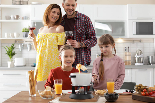 Happy family enjoying fondue dinner at home - Foto, afbeelding