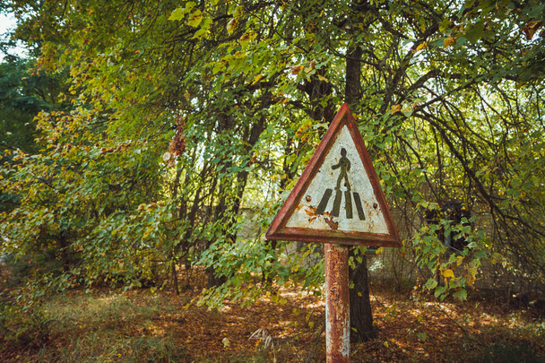 Oude roestige, versleten, bekrast rode driehoeksverkeer teken - voetgangersoversteekplaats radioactieve gebied in de stad Pripyat. Chornobyl exclusieve zone - Foto, afbeelding