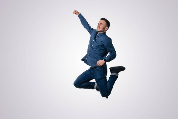 glücklich aufgeregt fröhlicher junger Mann springt und feiert Erfolg vor weißem Hintergrund - Foto, Bild