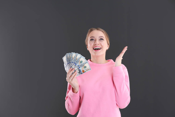 Portrait of emotional young woman with money on grey background - Photo, Image