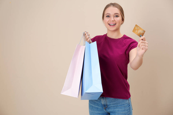Portrait of happy young woman with credit card and shopping bags on color background, space for text. Spending money - Fotografie, Obrázek