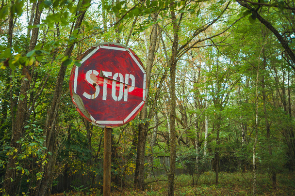 Stoppschild - altes rostiges, ausgefranstes, zerkratztes rotes Verkehrsschild in der radioaktiven Zone der Stadt Pripjat. Sperrzone für Tschornobyl - Foto, Bild
