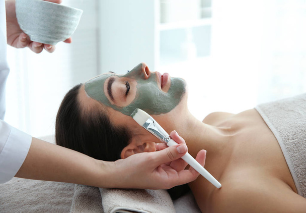 Cosmetologist applying mask on client's face in spa salon - Fotó, kép