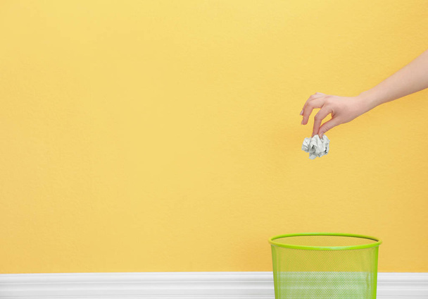 Woman throwing crumpled paper into metal bin against color background. Space for text - Foto, immagini