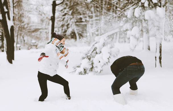 Ένα όμορφο νεαρό ζευγάρι είναι finghting στο χιόνι, το κορίτσι και το αγόρι που ρίχνουν επάνω στο χιόνι - Φωτογραφία, εικόνα