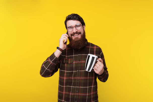 Bello uomo barbuto che parla al telefono con gli amici durante la pausa caffè
 - Foto, immagini