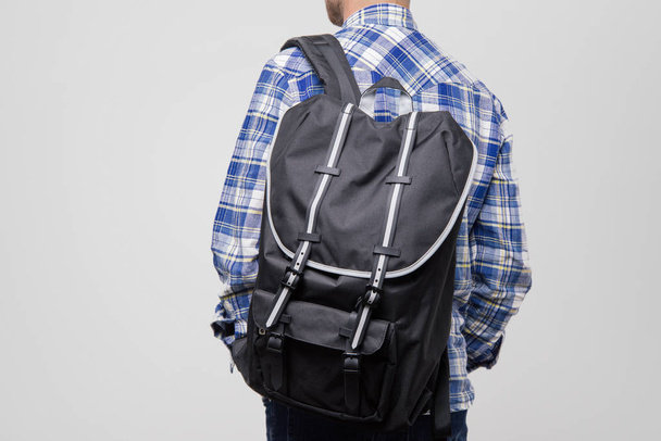 A back view of handsome guy in blue checkered shirt with black backcpack  - Fotó, kép