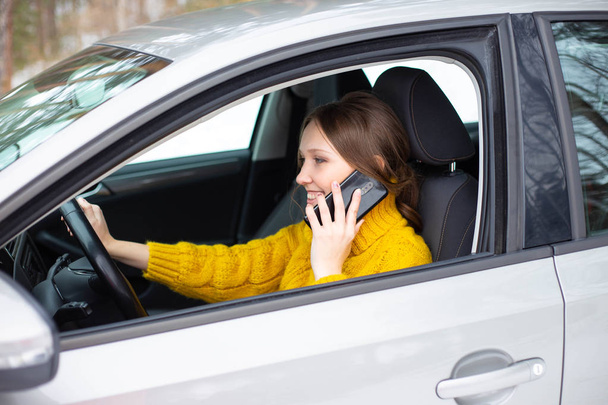 Woman is talking on her phone while driving a car - Photo, Image
