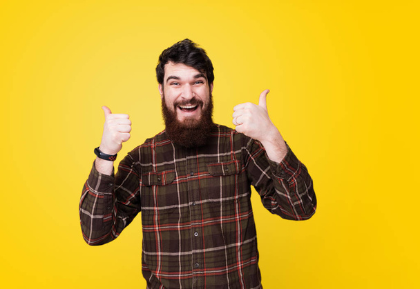 Portrait of happy funny  bearded man show sign thumb up and good luck - Фото, зображення