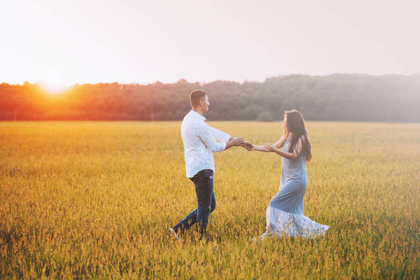 Photo of couple having fun in beautiful meadow on sunset or sunrise - Фото, зображення