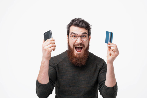 Elegante barbudo hipster está emocionado por su cuenta bancaria
  - Foto, imagen
