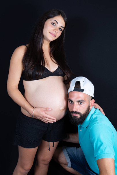 Handsome man is listening beautiful pregnant wife woman tummy and smiling - Foto, Bild