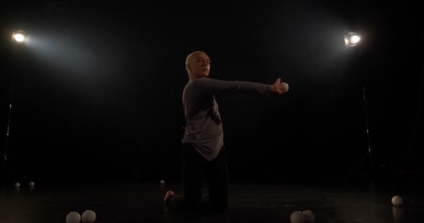 4k lassú mozgás-zsonglőr a fekete stúdióban, hogy trükk egy labdát. - Felvétel, videó
