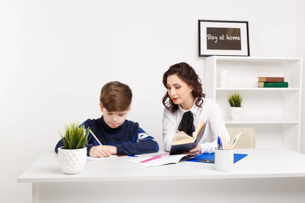 Female teacher helps teen boy to do his homework. Doing homework together. - Photo, Image