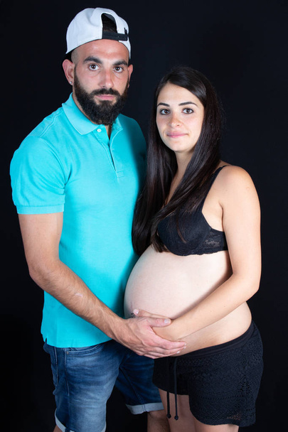 Young pregnant woman with her husband in black background - Foto, immagini