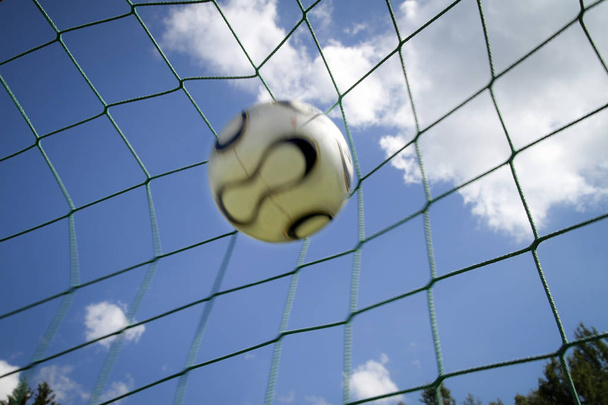 Bal binnen voetbal poort tegen blauwe heldere hemel - Foto, afbeelding