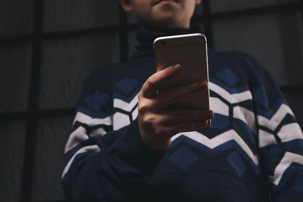 Teen boy holding phone and feeling sad. Victim of cyberbullying. Phone bullying. - Photo, Image