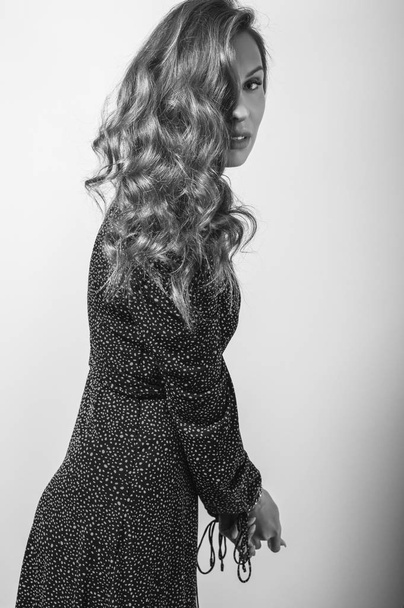 Beautiful girl in stylish dress posing in studio. Black-white photo. - Фото, зображення