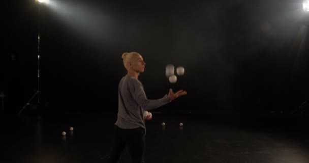 4k-jongleur in de zwarte Studio maakt trucs met vijf ballen. - Video