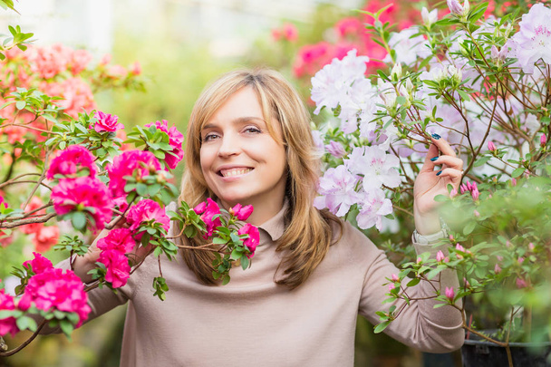 Beautiful woman watering plants and gardening in greenhouse. - Фото, зображення