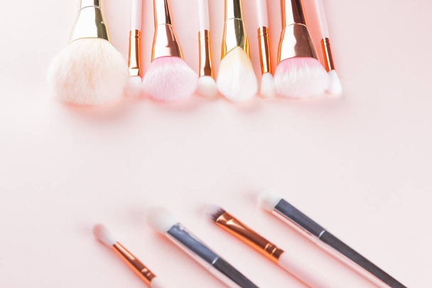 Makeup brushes on pink background. Set of golden makeup brushes, concept. Woman beauty accessory in pastel colors. Copy space. Flat lay - Zdjęcie, obraz