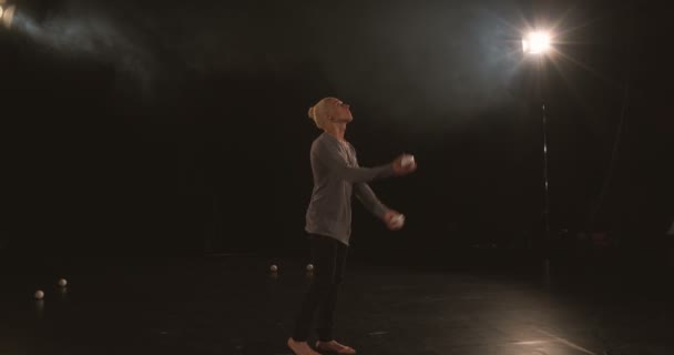 Žonglér v černém studiu dělá triky s pěti kuličkami - Záběry, video