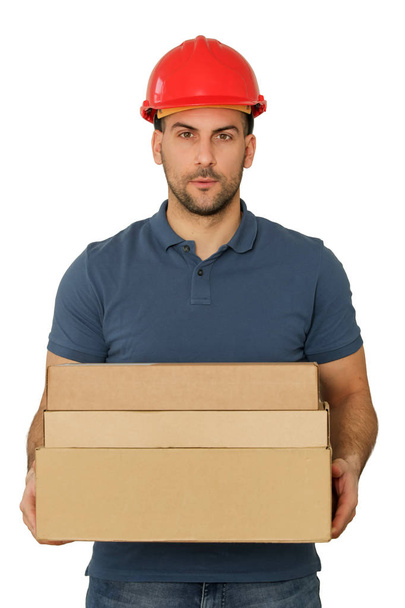 Young handsome worker in red helmet holding cardboard boxes, stu - Foto, afbeelding