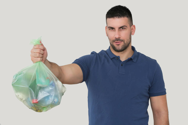 Studio portrait of handsome man holding green garbage bag isolat - 写真・画像