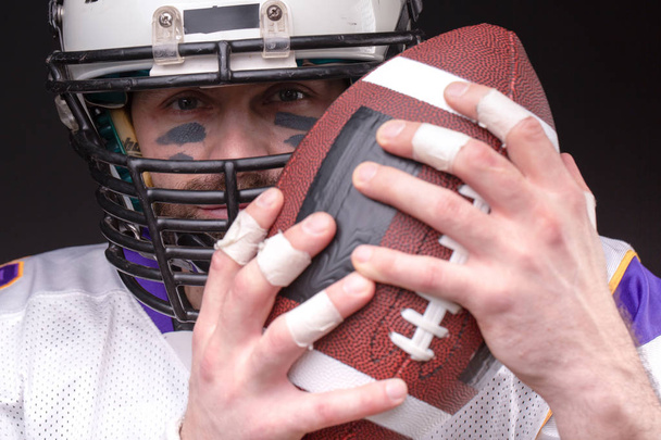 Ball for American football in front of footballer face - Foto, Imagem